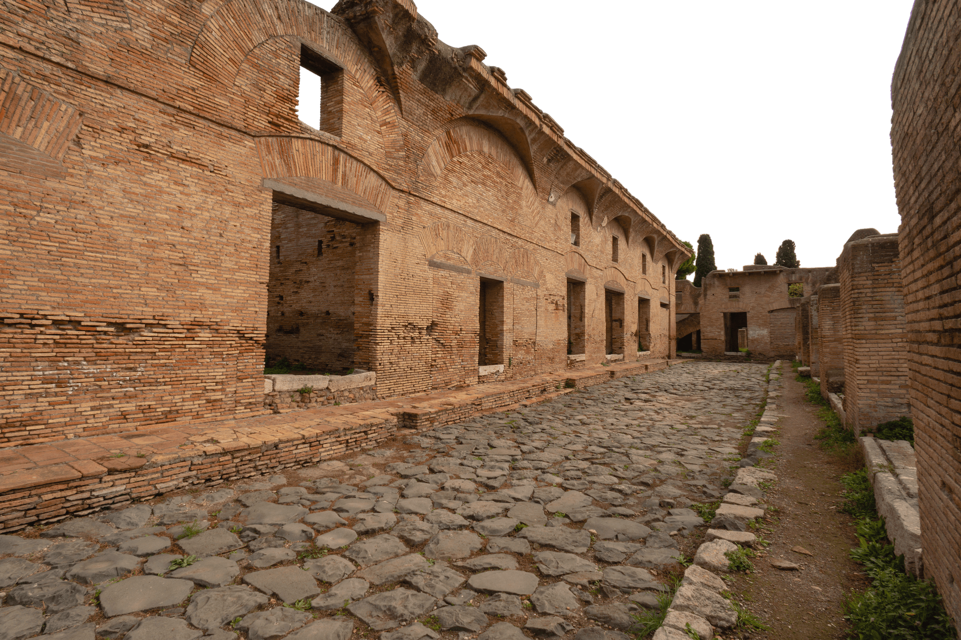 A street in Ostia with buildings on either side which have upper floors.
