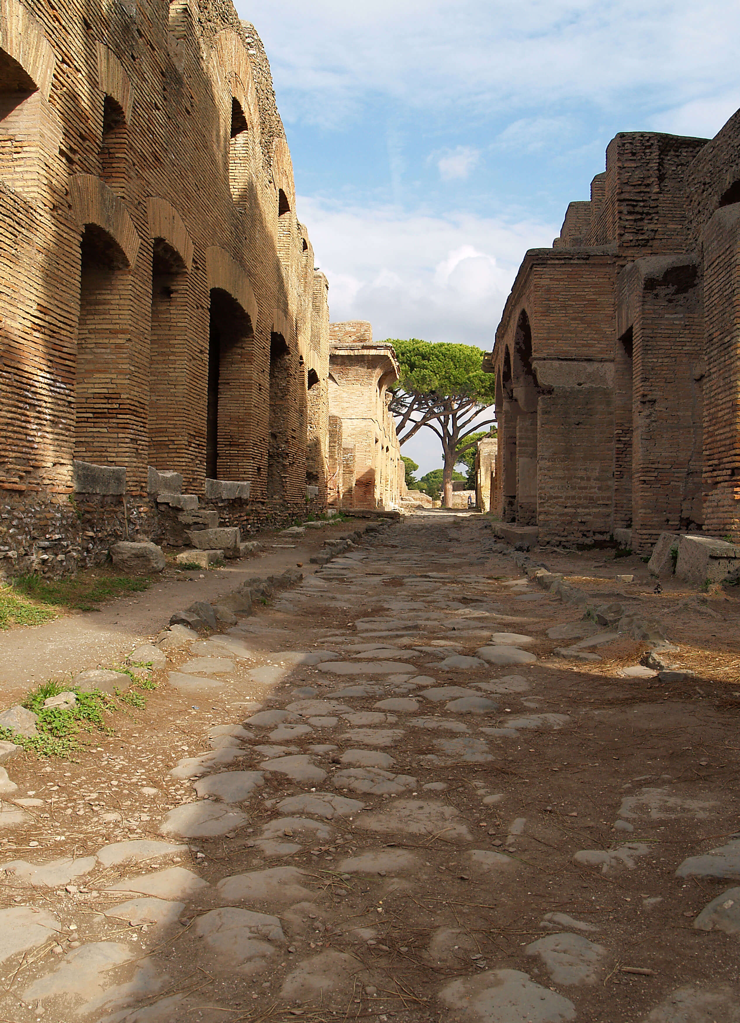 A street with apartment buildings from Ostia. The road is cobbled with big stones.