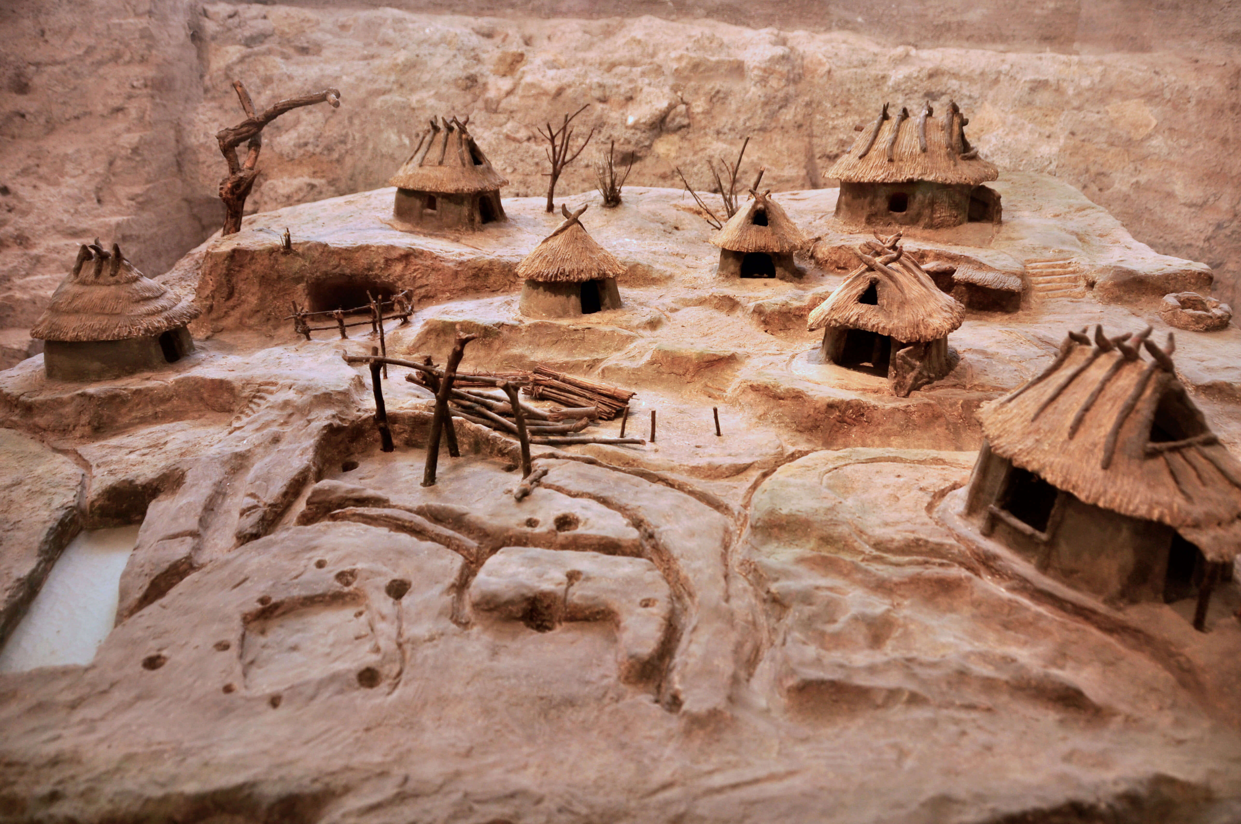 A small model which shows various wooden huts with muddy paths going between them.