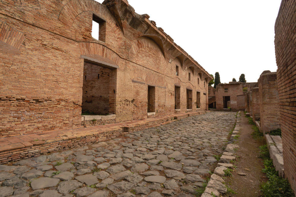 A street in Ostia with buildings on either side which have upper floors.