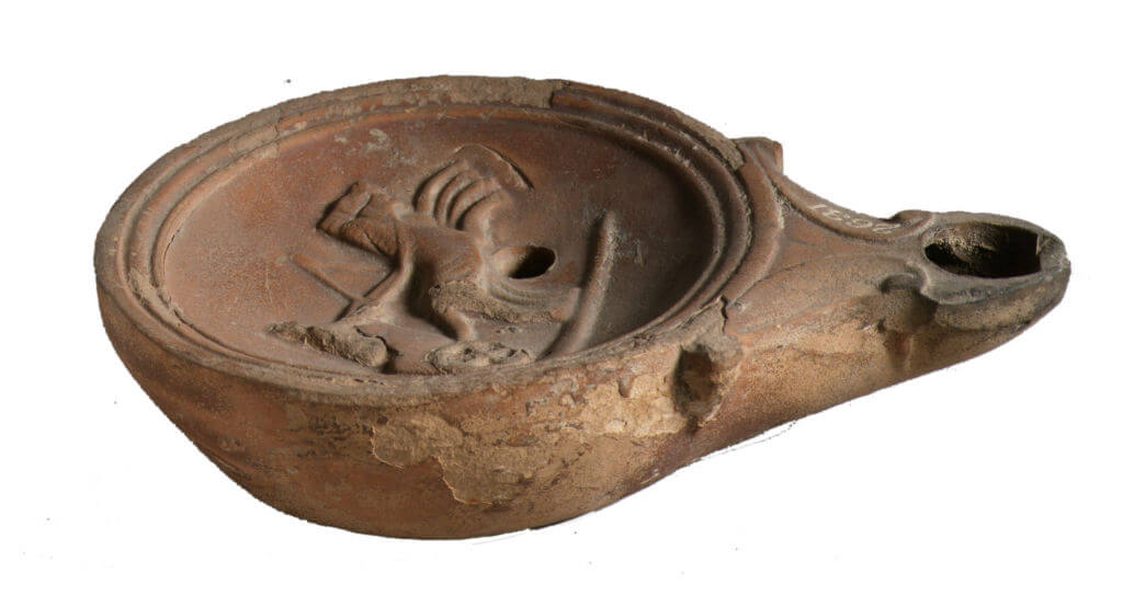 A ceramic oil lamp. It is round with a hole like a spout.