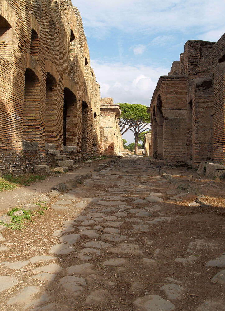 A street with apartment buildings from Ostia. The road is cobbled with big stones.