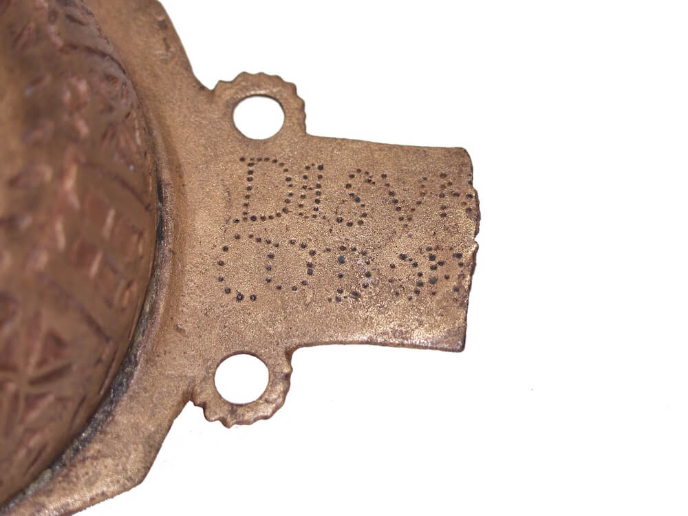 The decorated bronze handle of a metal dish.