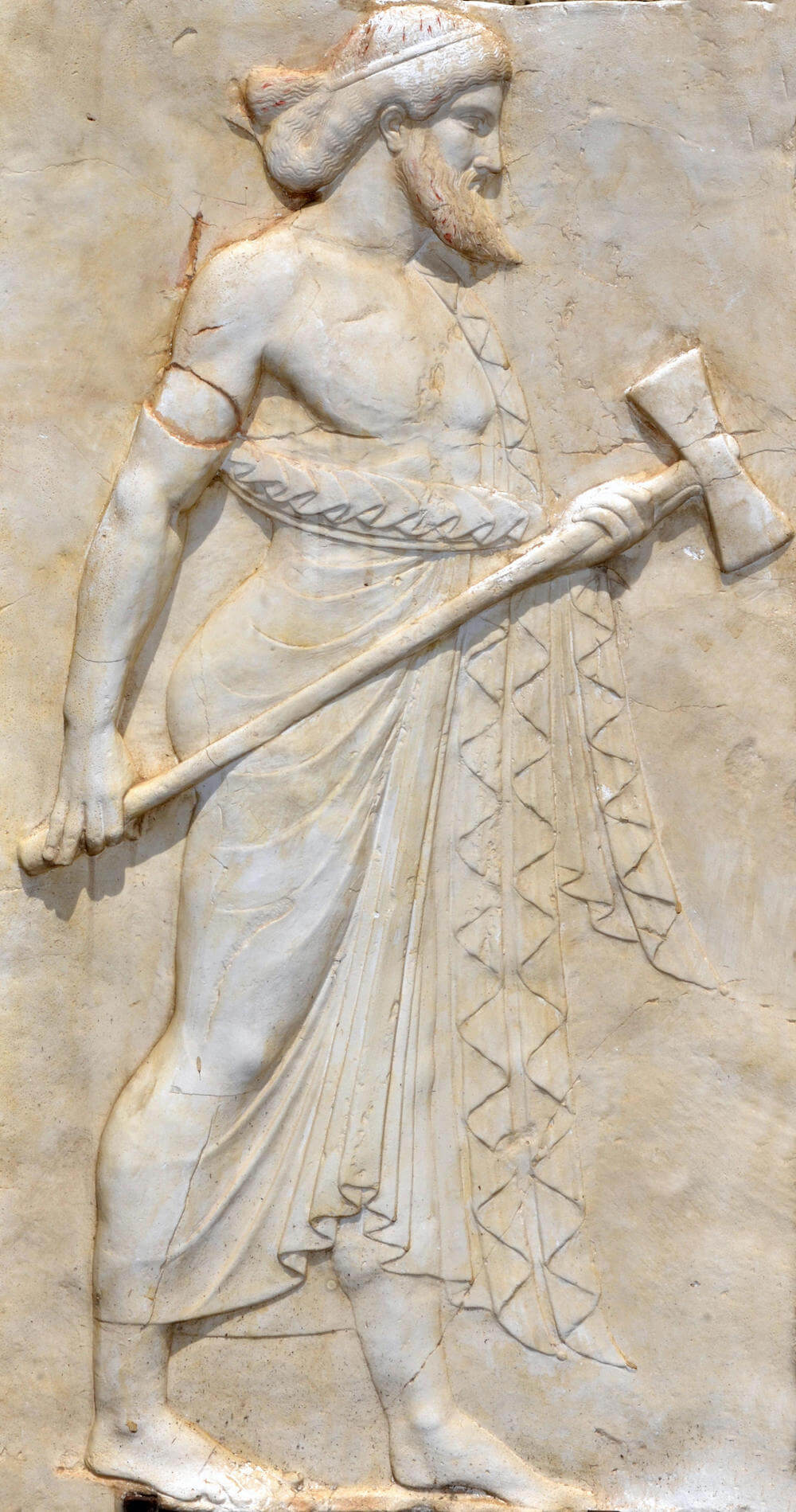 A marble relief showing the side profile of a man standing holding a large axe. He has pointed beard.