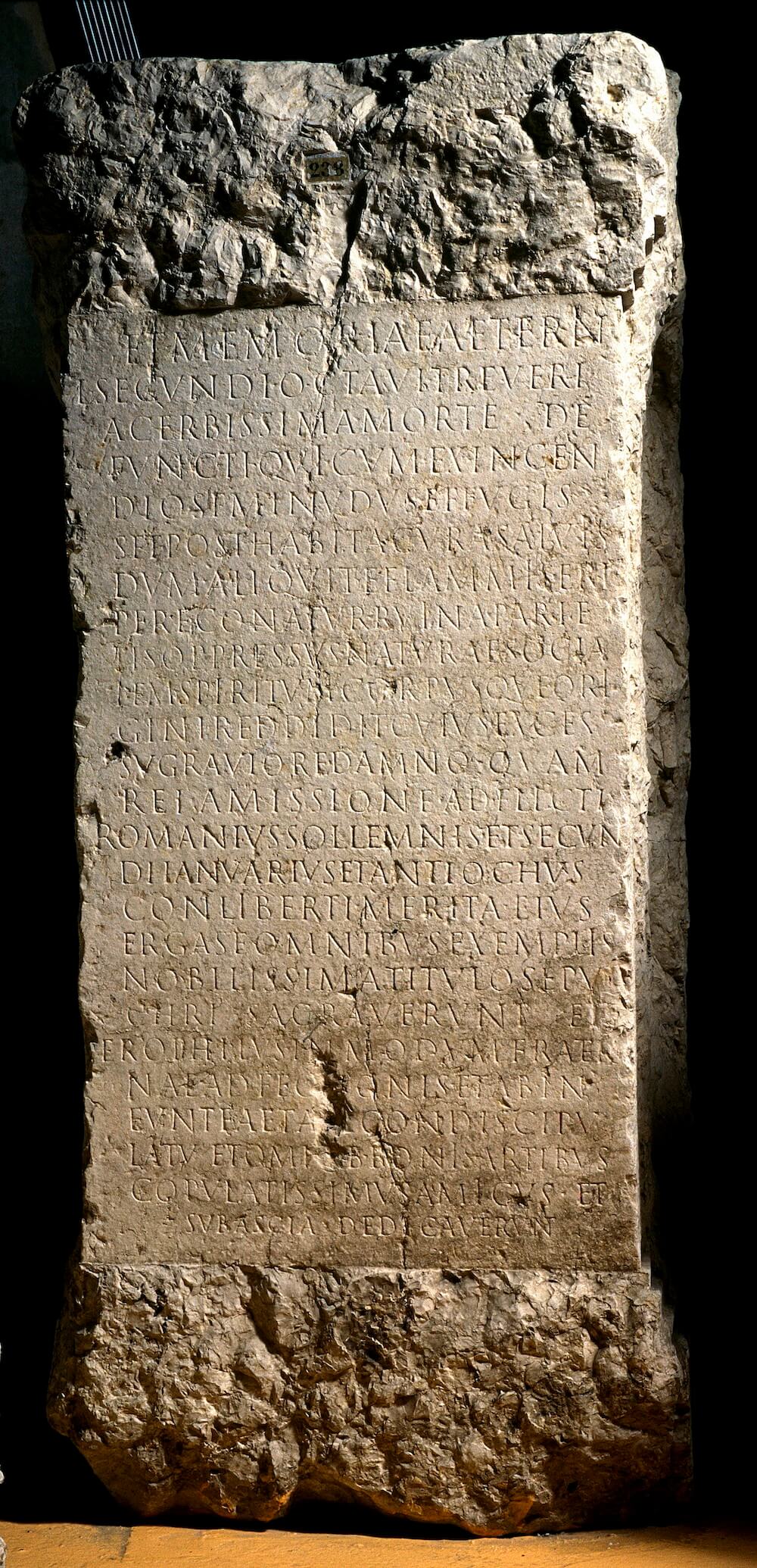 A rectangular tombstone with capital letters engraved across it.
