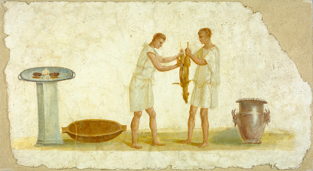 A Roman wall painting showing two men holding a dead animal and butchering it. On one side is a silver pot and on the other a small table with garlic on.