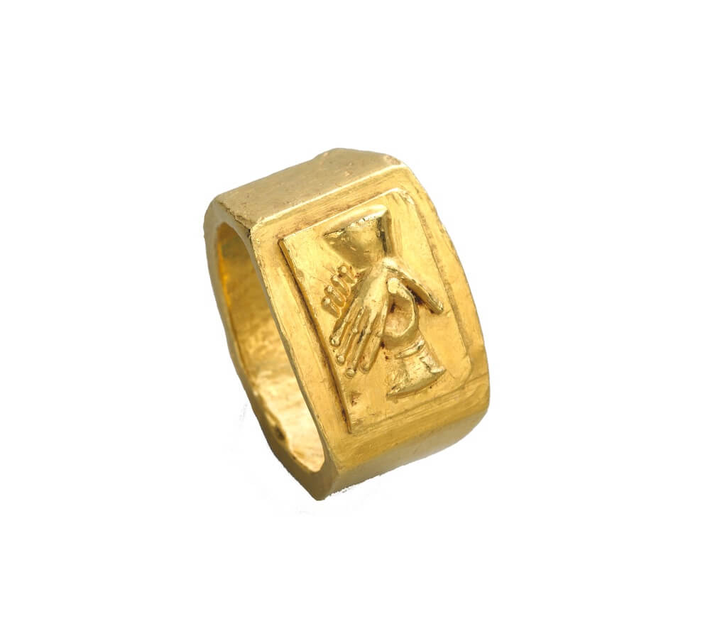 A chunky gold ring. On the top is a decoration of two hands joining.