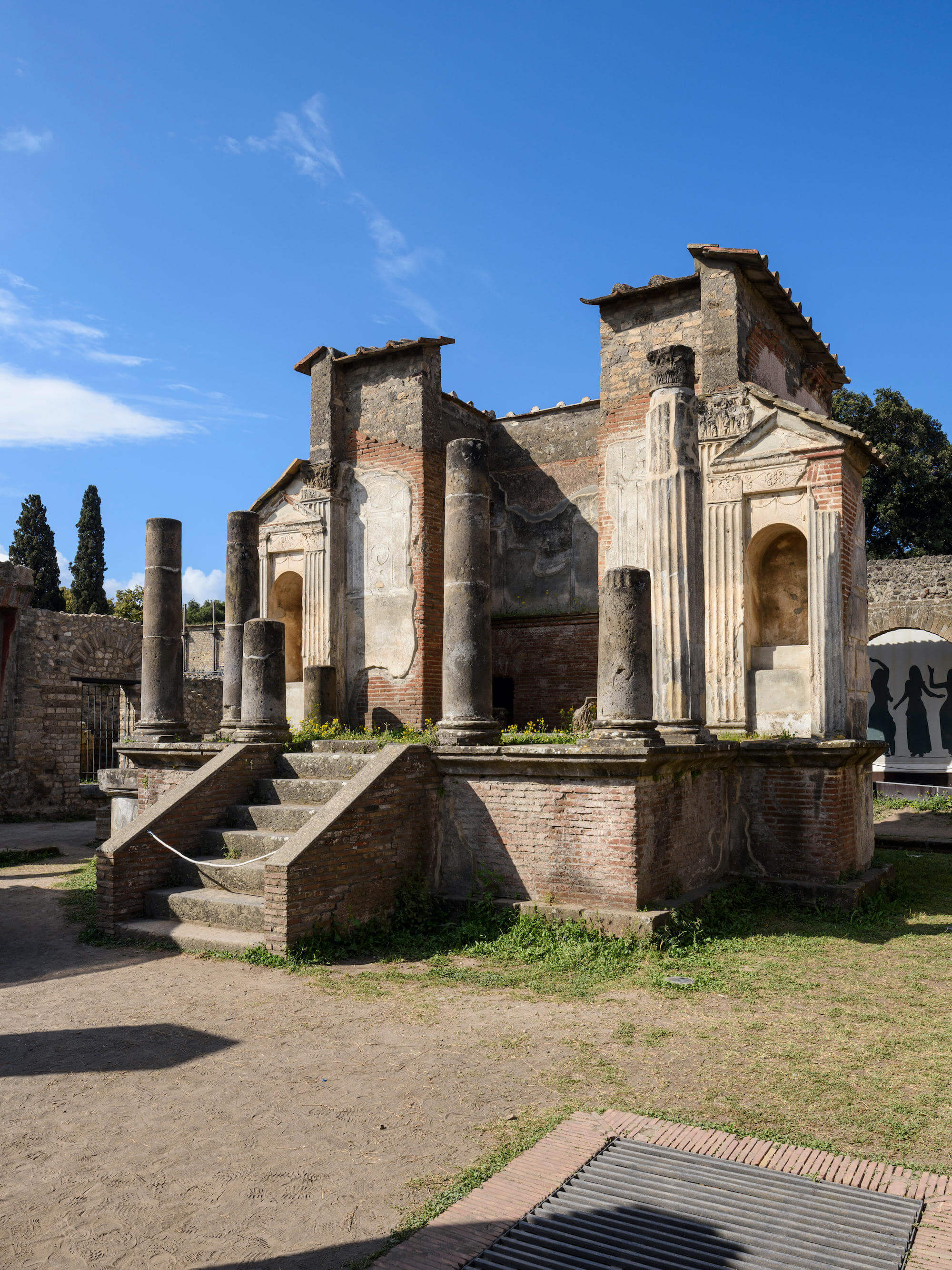 The remains of a temple. At the front are steps leading up and one either side of the front of the building are pillars. There is still some paint visisble on the outside of the building.