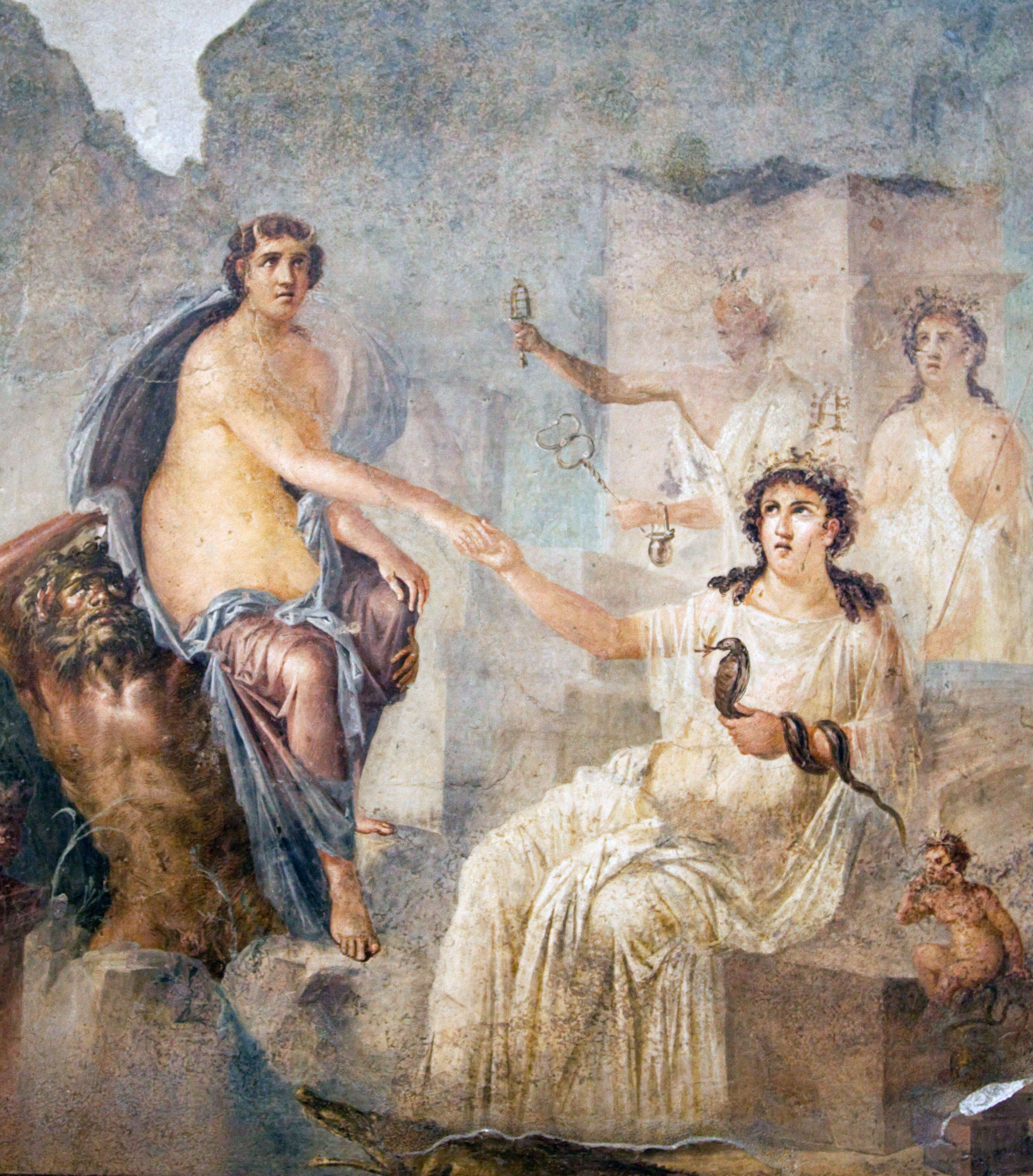 A wall painting showing a woman on the right sitting wearing a white dress and a crown. A snake is wrapping itself round her left arm. Her right hand is outstretched to another woman who is sitting on the shoulders of a topless man.