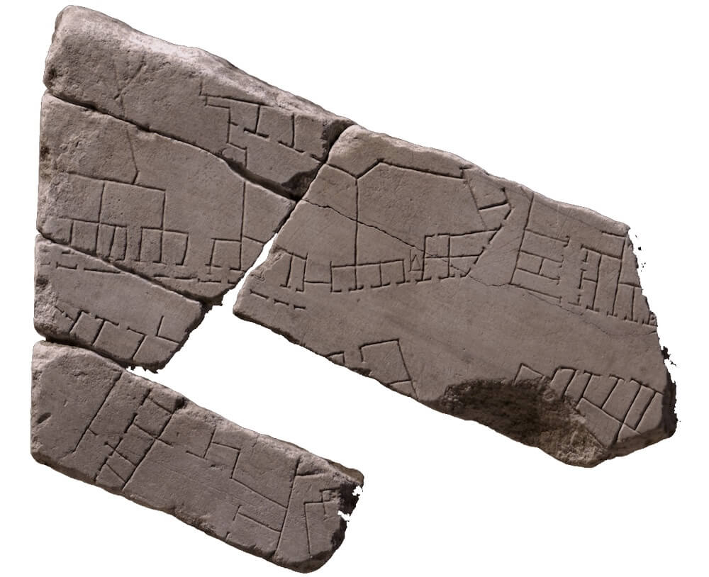 A broken stone fragment with markings on in little squares, lines, and dots.