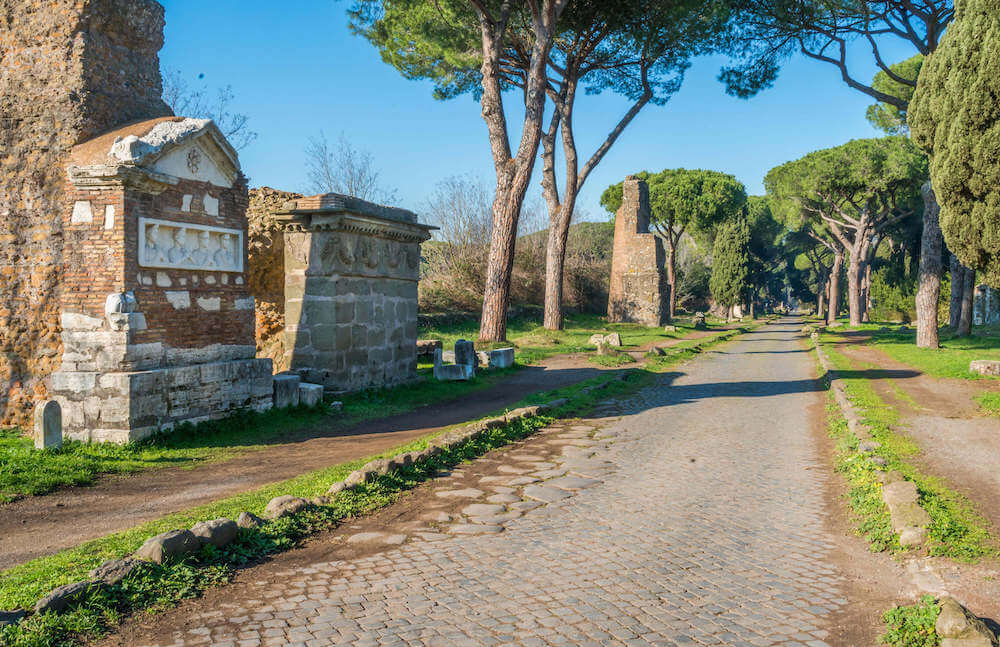 A pathway with tombs on the left side and trees along the edge.