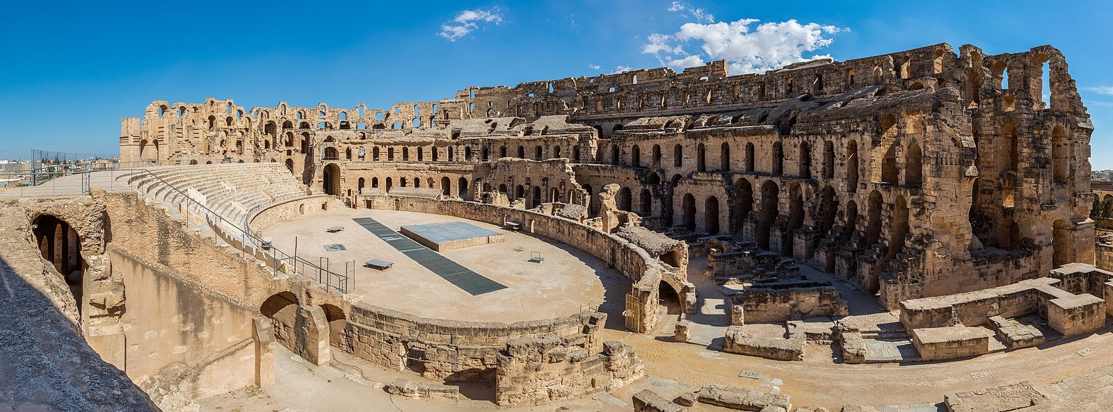 A photo of an oval stone structure with tiers of seats surrounded by tall arches. In the centre is a flat oval arena.