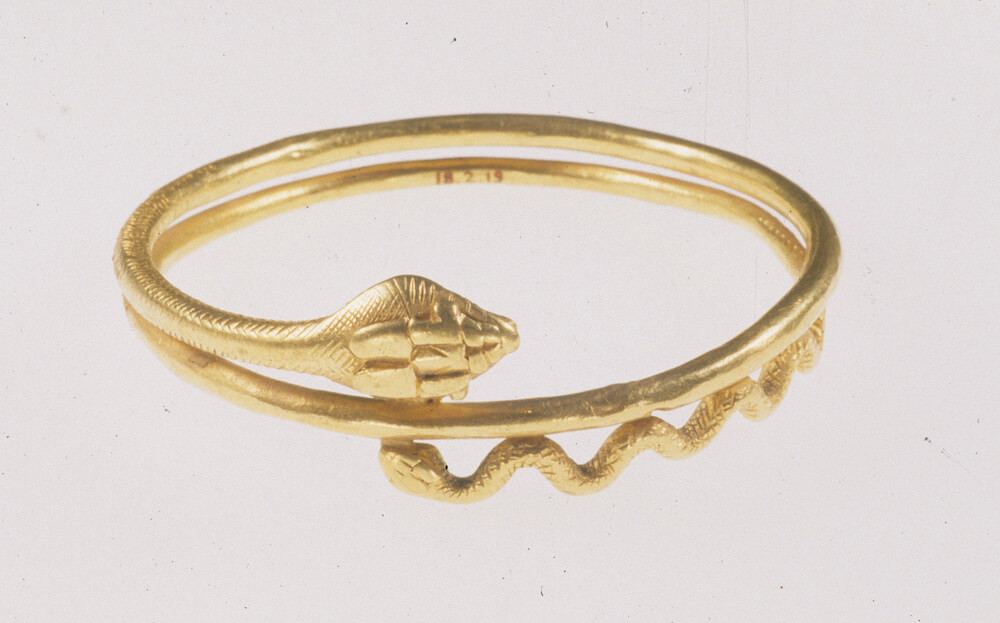A golden bracelet in the shape of a snake wrapped round on itself.