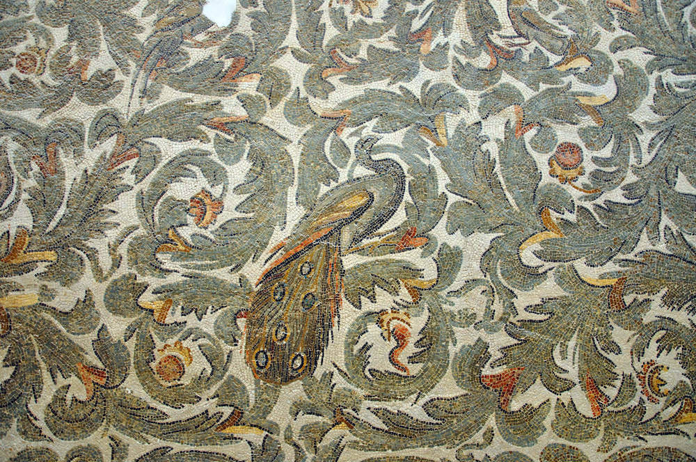 A mosaic with a peacock surrounded by swirling leaves in greens and orange.