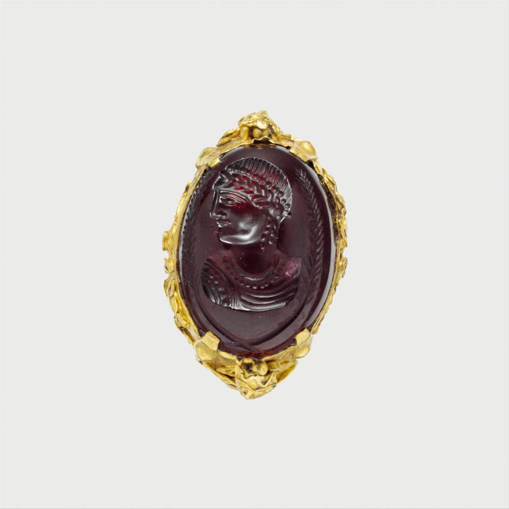 The dark red stone set in a gold ring. The portrait of a woman is carved into the stone.