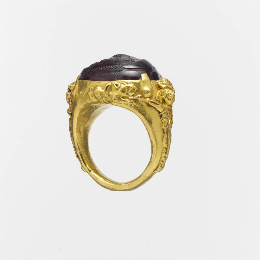 A gold ring with a dark-red stone inset on top.