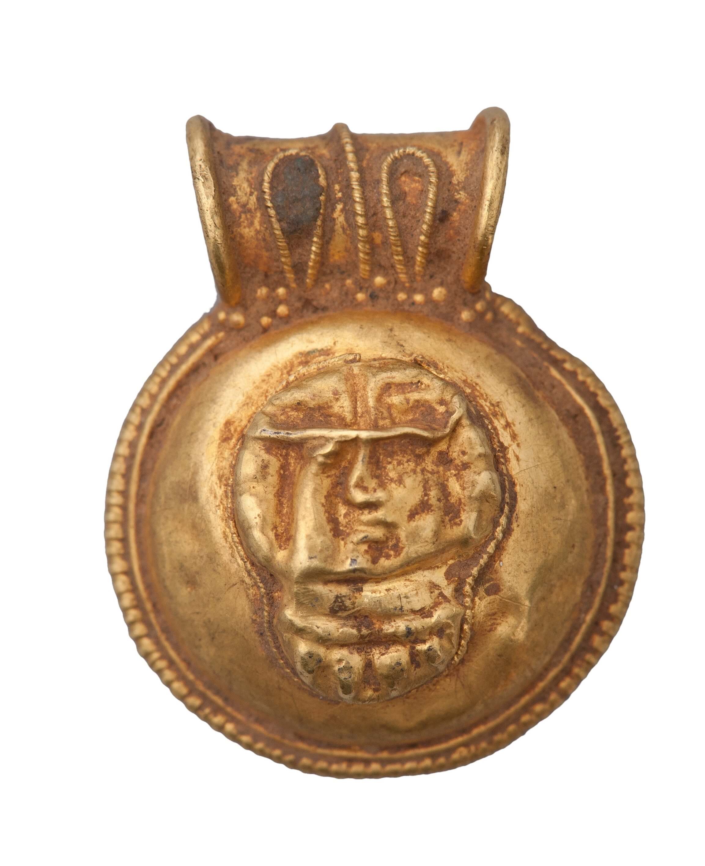 A circular golden item with a lip at the top for stringing a cord through. On the centre is imprinted a rough face.