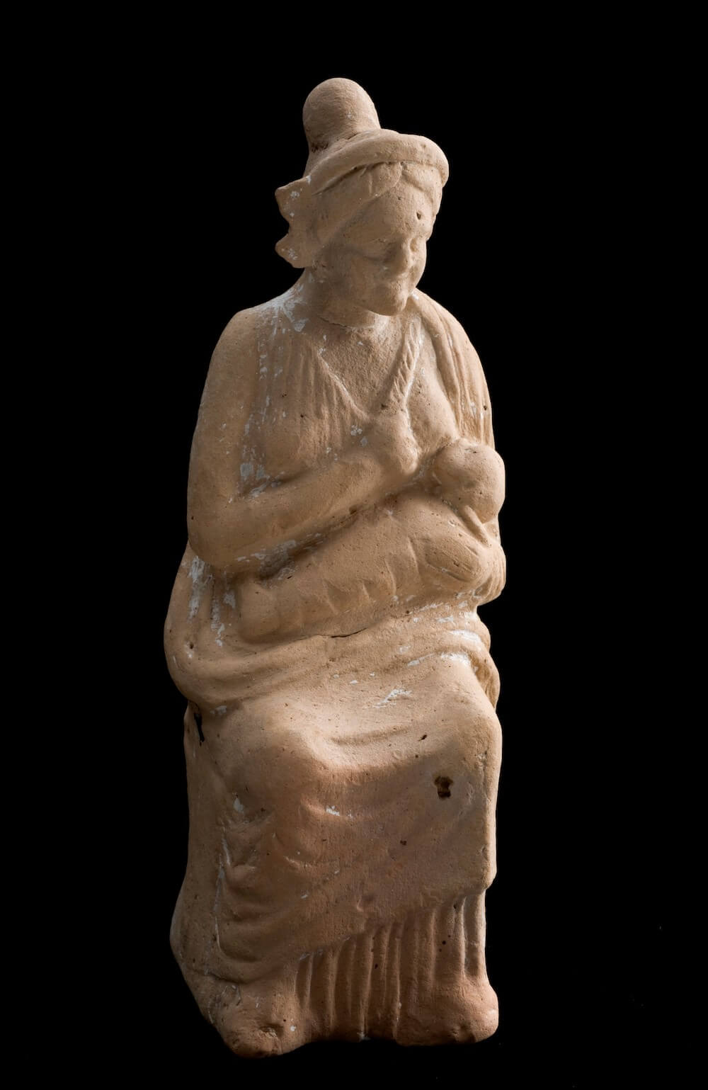 A small statuette of a seated woman breastfeeding her baby on her lap.