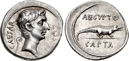 Two sides of a silver coin. One side shows a male face in profile, the other a crocodile.