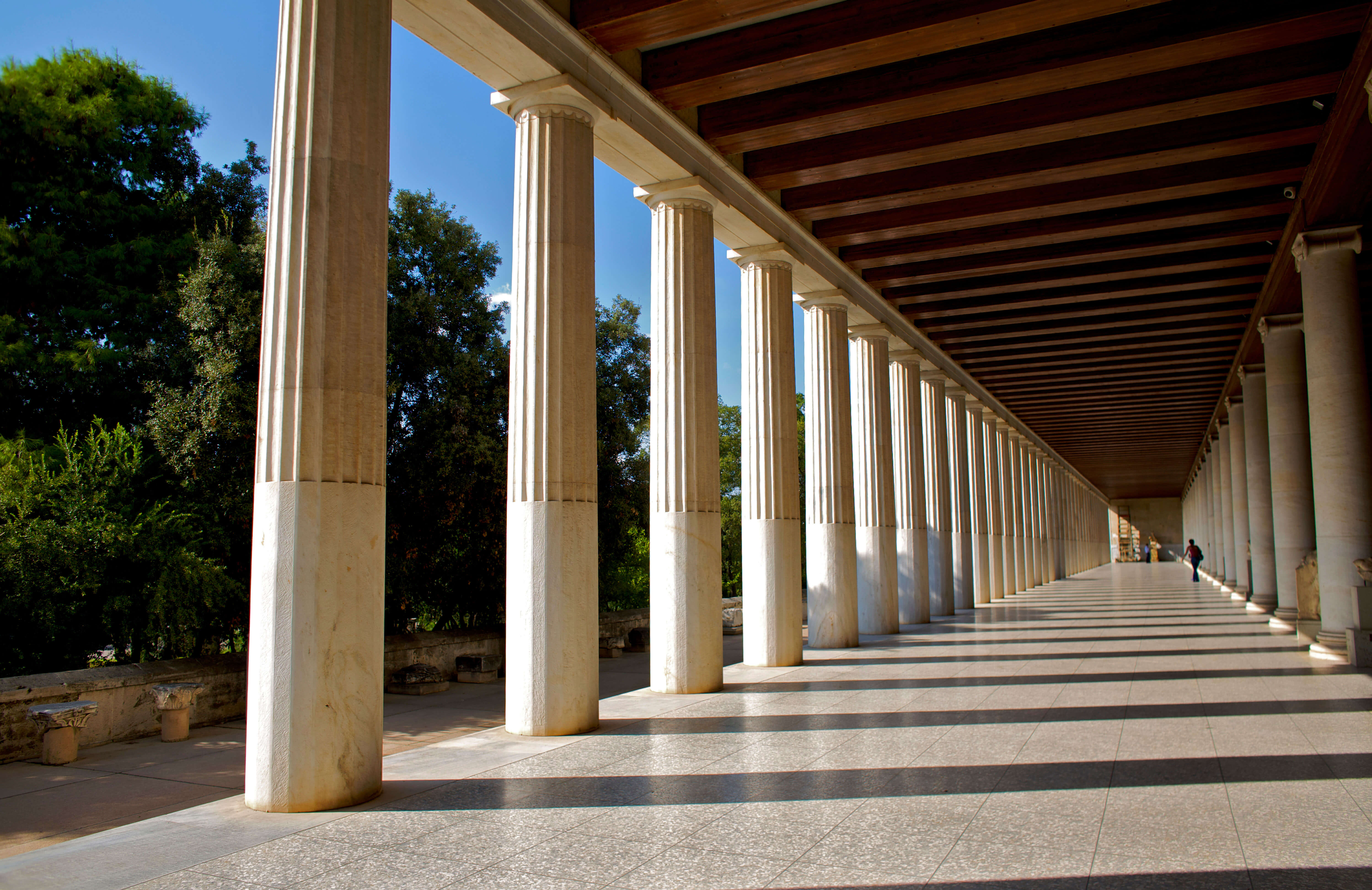 A long covered portico with marble, fluted columns along one side.