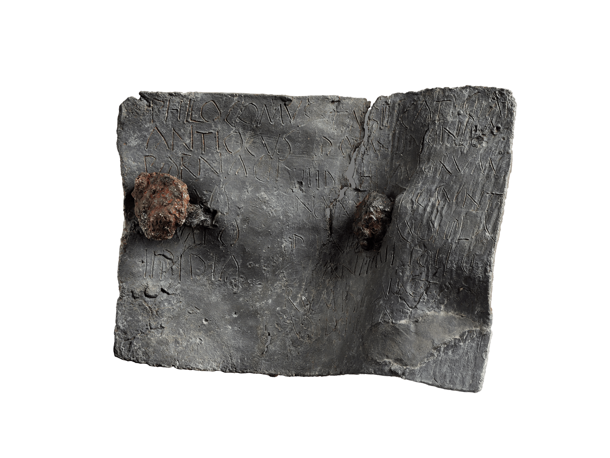 A roughly rectangular piece of dark grey metal which is slightly crinkled. The surface has capital letters scratched into the surface.