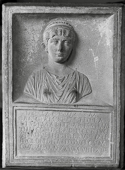 A black and white image of a funerary monument. It has a carved portrait of a young girl and below text carved into the stone, all in capital letters.