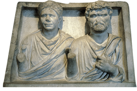 A stone relief showing a woma and a man side by side. the woman has her hair styled in plaits around her head. The man has a beard and wears a toga.