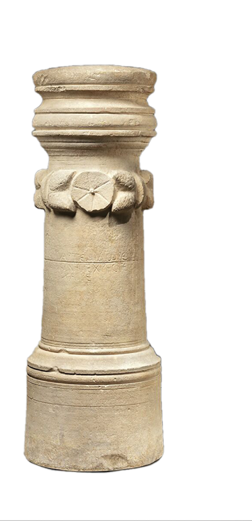 A cylindrical stone which has been carved with decorative rings and a patter of basic flowers above halfway down.