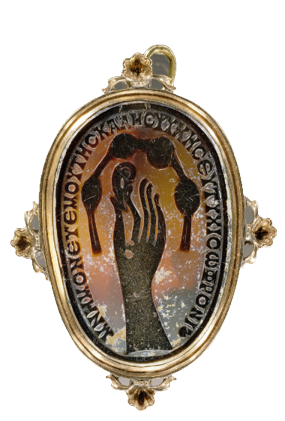 An oval stone with the motif of a hand reaching up an ear carved into the surface. Above the ear is a string of four circles joined by a string. Around the edge are Greek letters. The stone is held in a metal casing.