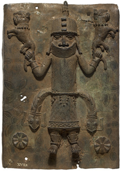A rectangular sheet of dark metal decorated with a stylized and symmetrical image of a man wearing armor holding a creature like a lion in each hand. From his belt protrude two fishes.
