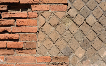 A photo of a brick wall. On the left the bricks are laid horizontally and are rectangular. On the right the bricks are cut into diamonds and laid in a criss-cross pattern.