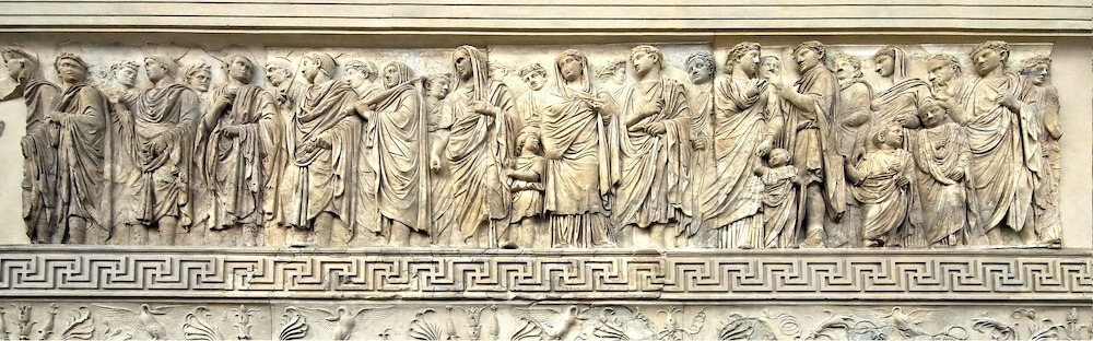 A long stone carving showing a procession of people dressed formally.