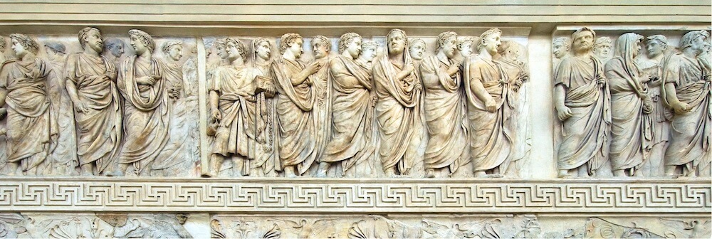 A long stone carving showing a procession of people dressed formally.