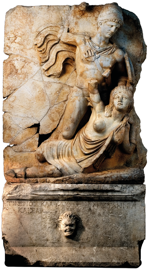 A stone scultpure carved in relief. On it a man who is nude apart from a helmet and cloak stands above a woman who is lying on the floor. With one hand he holds her by her hair, the other hand is raised. The woman is wearing a dress which bears one breast.