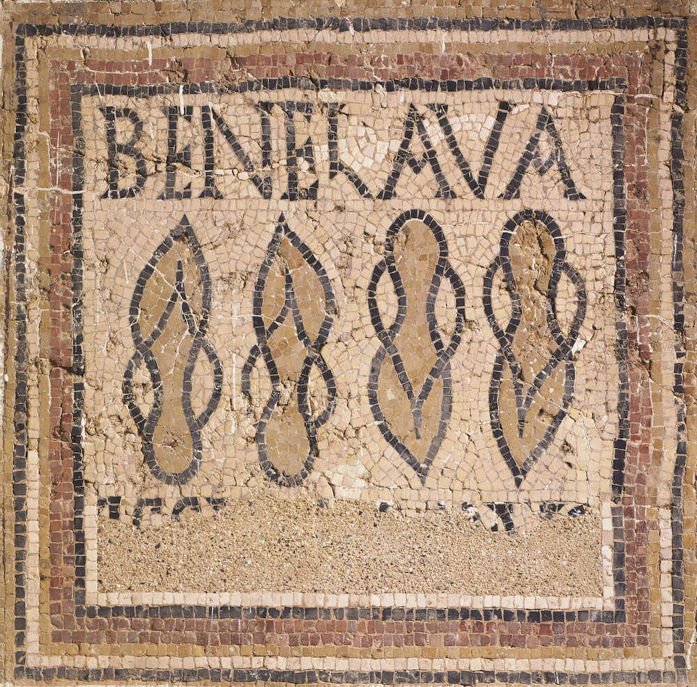 A mosaic showing two pairs of Roman sandals that look like flip flops, one pair facing up, one pair facing down. Above is the text BENE LAVA.