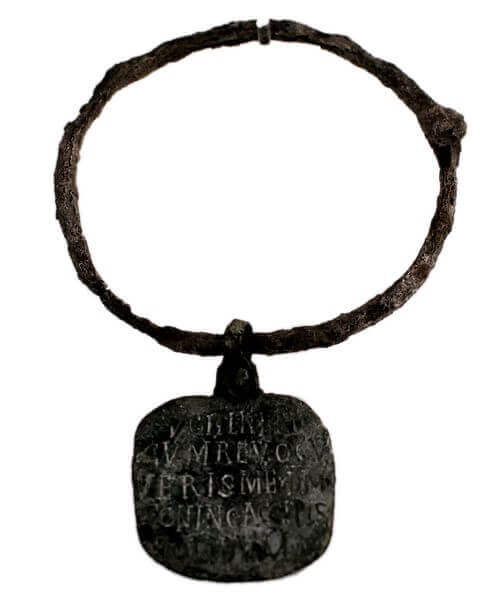 A photograph of a rusted metal collar with a large metal tag attached.