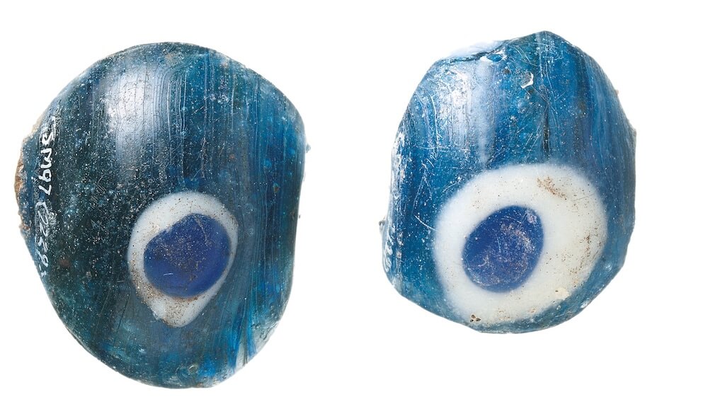Two blue glass beads, each with a blue circle within a white ring on them.