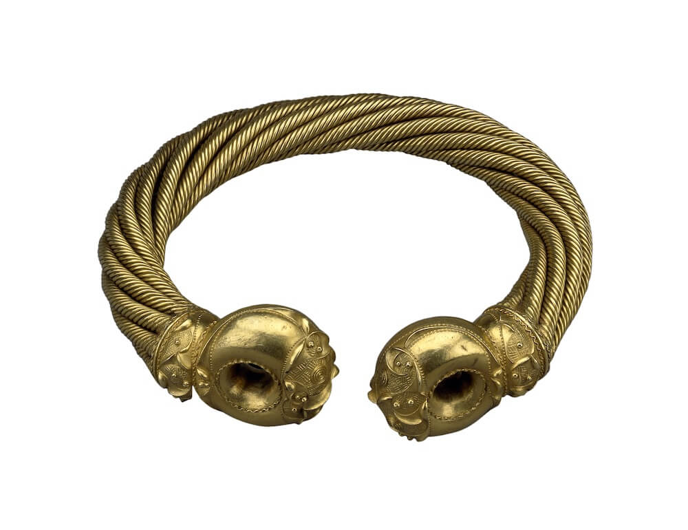 A gold torc, with spiralling decorations along most of its length, and delicate metalwork at each end.